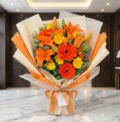 Bouquet LIRICA con lirios naranjas vibrantes, rosas amarillas abiertas y gerberas rojas, envuelto en papel coreano elegante s