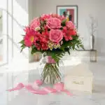 Bouquet ORLENA con rosas rosadas, gerberas y alstroemerias en jarrón de cristal, sobre mármol blanco con tarjeta 'Para Ti' y