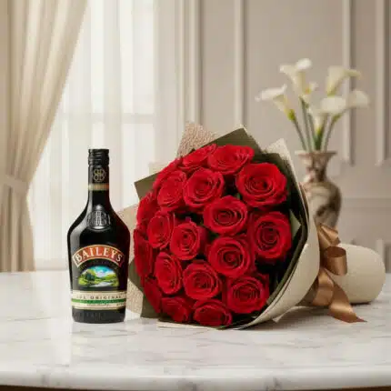 Elegante bouquet de rosas rojas frescas y una botella de Baileys original, presentado sobre una superficie de mármol en un en