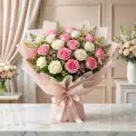 Bouquet de 18 rosas rosadas y blancas, con follaje verde, envuelto en papel coreano rosa claro y atado con un lazo de satén,