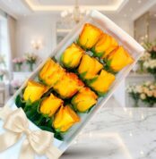 Caja de 12 rosas amarillas frescas y abiertas con un moño elegante, sobre una superficie de mármol en un entorno de florister