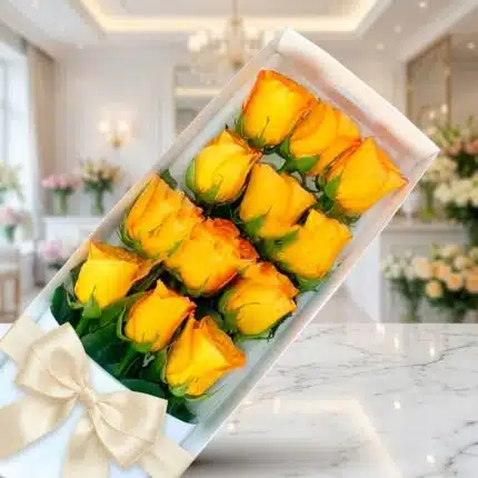 Caja de 12 rosas amarillas frescas y abiertas con un moño elegante, sobre una superficie de mármol en un entorno de florister