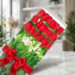 Caja transparente con 18 rosas rojas frescas y alstroemerias blancas, atada con un elegante moño rojo, sobre una superficie d