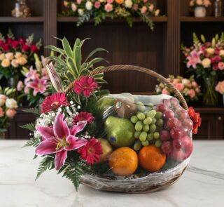Canasta Frutal CARMINE con lirios rosados, gerberas fucsia, follaje verde y frutas frescas como uvas, manzanas, naranjas y ki