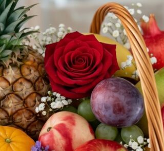 Primer plano extremo de una rosa roja vibrante con gotas de rocío, rodeada de frutas frescas como piña, uvas, ciruela y manza