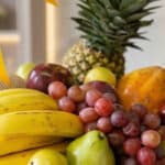 Primer plano extremo de una canasta de frutas Sirio con uvas rojas, peras verdes, plátanos amarillos, manzanas y piña, destac