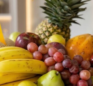 Primer plano extremo de una canasta de frutas Sirio con uvas rojas, peras verdes, plátanos amarillos, manzanas y piña, destac