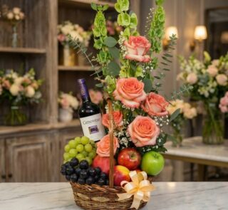 Canasta gourmet CAPRICE con rosas frescas color salmón, uvas verdes y moradas, manzanas rojas y verdes, duraznos y una botell