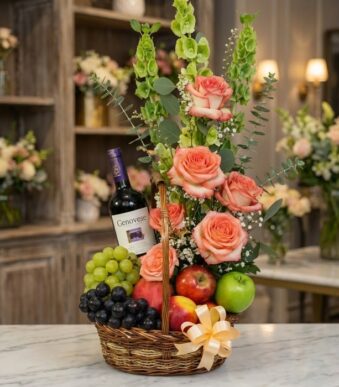 Canasta gourmet CAPRICE con rosas frescas color salmón, uvas verdes y moradas, manzanas rojas y verdes, duraznos y una botell