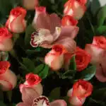 Primer plano extremo de una canasta de rosas y orquídeas con textura hiperrealista, gotas de rocío y colores vibrantes bajo l