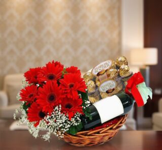 Cesta de regalo ROMA con gerberas rojas, vino tinto y chocolates Ferrero Rocher, ideal para ocasiones especiales.