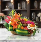 Cesta frutal THALIA con lirios naranjas, anturios rosas, rosas variadas, eustomas blancas y frutas frescas como uvas, manzana