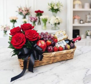 Elegante cesta de regalo con rosas rojas frescas, vino tinto, chocolates Ferrero Rocher y una selección de frutas variadas co