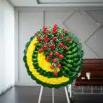 Corona fúnebre Adela con rosas rojas y flores amarillas, diseño moderno para tanatorio, simbolizando condolencias y respeto.