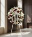 Corona de homenaje fúnebre Ararat con flores blancas y rojas, lirios, rosas y margaritas, sobre un trípode en una sala de vel