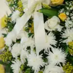 Fotografía macro premium de la Corona Fúnebre Estamos Contigo, mostrando texturas hiperrealistas de pétalos blancos, cremas y