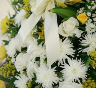 Fotografía macro premium de la Corona Fúnebre Estamos Contigo, mostrando texturas hiperrealistas de pétalos blancos, cremas y