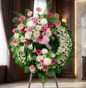 Corona fúnebre solemne "Homenaje a Mathias" con lirios blancos, gerberas rosas y crisantemos blancos, en una sala de velación