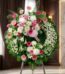 Corona fúnebre solemne "Homenaje a Mathias" con lirios blancos, gerberas rosas y crisantemos blancos, en una sala de velación