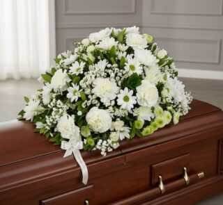 Cubre caja fúnebre Epifania con flores blancas y cinta de condolencia, vista desde un ángulo diferente y composición renovada