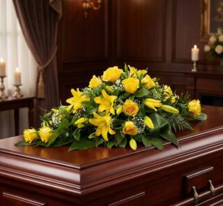 Elegante cubre caja fúnebre con rosas amarillas y lirios, sobre un ataúd de madera oscura en un ambiente solemne y bien ilumi