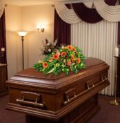 Cubre caja fúnebre 'Paz Eterna' con flores frescas y vibrantes sobre un ataúd de madera oscura en un entorno elegante y bien