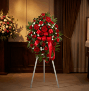 Pedestal fúnebre 'Homenaje Eterno a Andrés' con rosas rojas, claveles blancos y follaje verde, presentado en una elegante sal