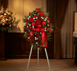 Pedestal fúnebre 'Homenaje Eterno a Andrés' con rosas rojas, claveles blancos y follaje verde, presentado en una elegante sal