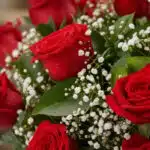 Primer plano extremo de un jarrón con 12 rosas rojas, mostrando texturas hiperrealistas, gotas de rocío y follaje verde con f