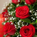 Primer plano extremo de un Jarrón Dulce Amor con rosas rojas frescas, gotas de rocío sutiles y follaje verde, ideal para rega