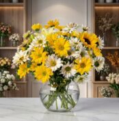 Jarron Floral Agatha con margaritas amarillas y blancas, girasoles y lirios, sobre marmol en floristeria premium.