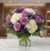 Jarron Floral VITTORIA con rosas lilas, hortensias blancas y muscaris azules, sobre una superficie de mármol en un entorno de