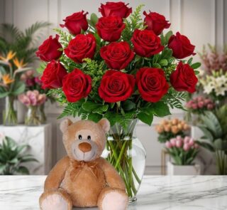 Jarrón Llévame Contigo con un exuberante arreglo de rosas rojas frescas y un adorable oso de peluche sentado al frente, sobre