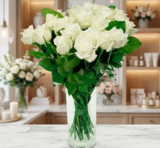 Jarrón de cristal con un gran ramo de rosas blancas frescas y abiertas, sobre una superficie de mármol en un entorno de flori