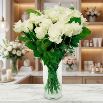 Jarrón de cristal con un gran ramo de rosas blancas frescas y abiertas, sobre una superficie de mármol en un entorno de flori