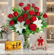 Jarrón Todo Para Ti con un exuberante arreglo floral de rosas rojas y lirios blancos, acompañado de un osito de peluche y cho