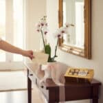 Arreglo floral Orquídea ESTRELLA de doble vara con flores blancas y centro morado, lazo rosa, caja de chocolates Ferrero Roch