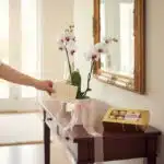 Arreglo floral Orquídea ESTRELLA de doble vara con flores blancas y centro morado, lazo rosa, caja de chocolates Ferrero Roch