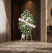 Pedestal conmemorativo Legado de Marcos con arreglo floral fúnebre blanco, lirios y rosas, en sala de velación elegante con i