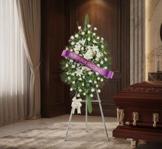 Pedestal conmemorativo Legado de Marcos con rosas blancas y lirios, cinta morada 'En Profunda Sinceridad', junto a un ataúd e