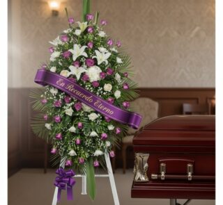 Pedestal fúnebre Esteban con rosas moradas y blancas, lirios, y cinta 'En Recuerdo Eterno' junto a un ataúd en sala de velaci
