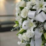 Fotografía macro premium del Pedestal Fúnebre Hasta Pronto, mostrando texturas hiperrealistas de rosas blancas, lirios y foll