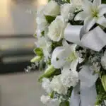 Fotografía macro premium del Pedestal Fúnebre Hasta Pronto, mostrando texturas hiperrealistas de rosas blancas, lirios y foll