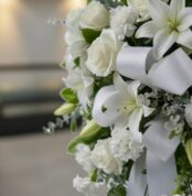 Fotografía macro premium del Pedestal Fúnebre Hasta Pronto, mostrando texturas hiperrealistas de rosas blancas, lirios y foll