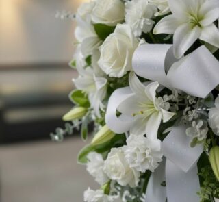 Fotografía macro premium del Pedestal Fúnebre Hasta Pronto, mostrando texturas hiperrealistas de rosas blancas, lirios y foll