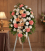 Pedestal fúnebre de homenaje para Timoteo, con arreglo floral de claveles coral, rosas durazno y crisantemos blancos, en sala
