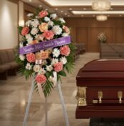 Pedestal fúnebre de homenaje para Timoteo con arreglo floral de claveles, rosas y crisantemos, cinta morada con mensaje de pé