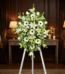 Pedestal fúnebre Inmaculada con lirios blancos, gerberas y follaje verde, presentado en una elegante sala de velación con ilu