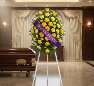 Pedestal fúnebre 'Legado Sereno' con rosas y claveles amarillos, cinta morada 'Sentido Pésame', junto a un ataúd en sala de v