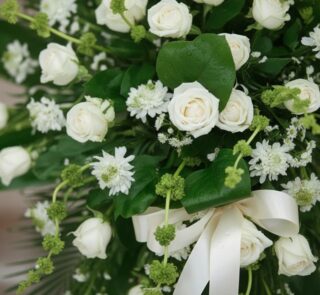 Fotografía macro premium del Pedestal Fúnebre Nunca te Olvidaré, mostrando rosas blancas, follaje verde con rocío sutil y una